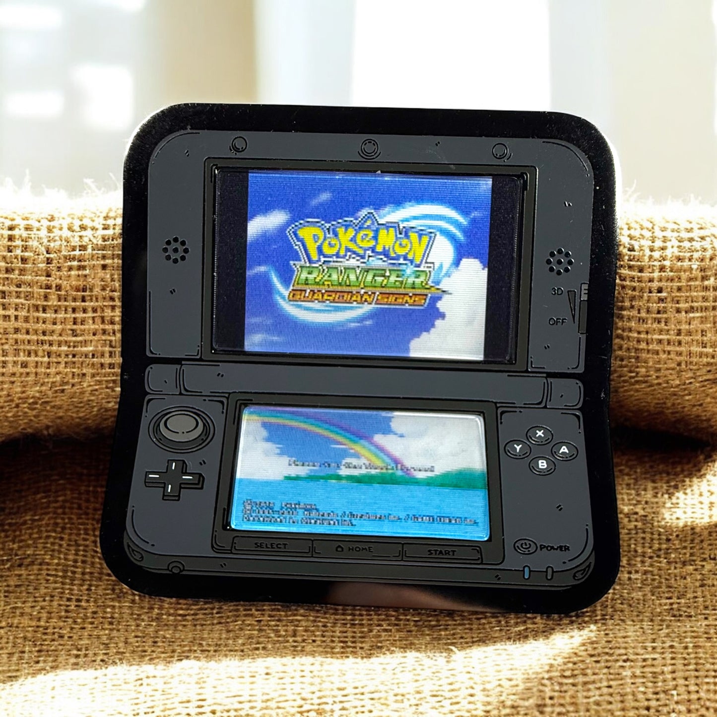 Black Nintendo DS with two screens displaying 'Pokémon Ranger: Guardian Force' game on a textured surface.