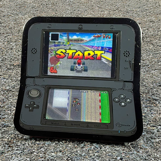 Black handheld gaming console displaying a racing game on two screens.