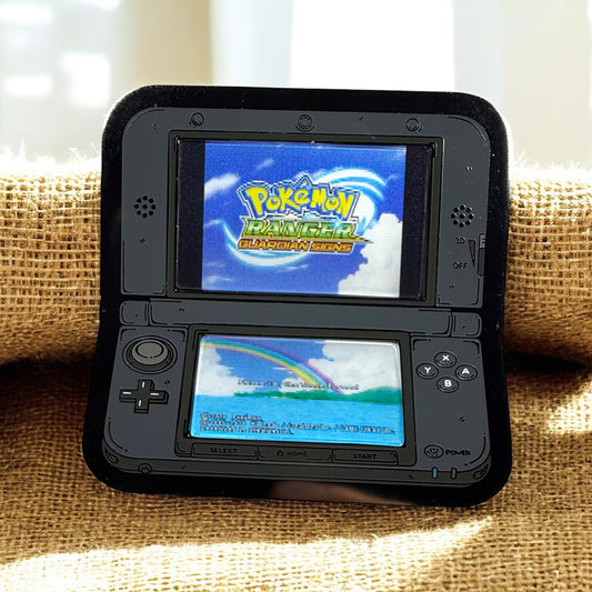 Black Nintendo DS with two screens displaying 'Pokémon Ranger: Guardian Force' game on a textured surface.