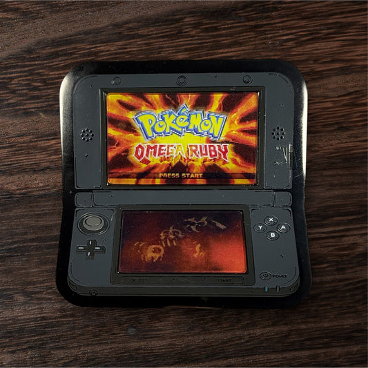 Nintendo DS device displaying 'Pokémon Omega Ruby' on a wooden surface