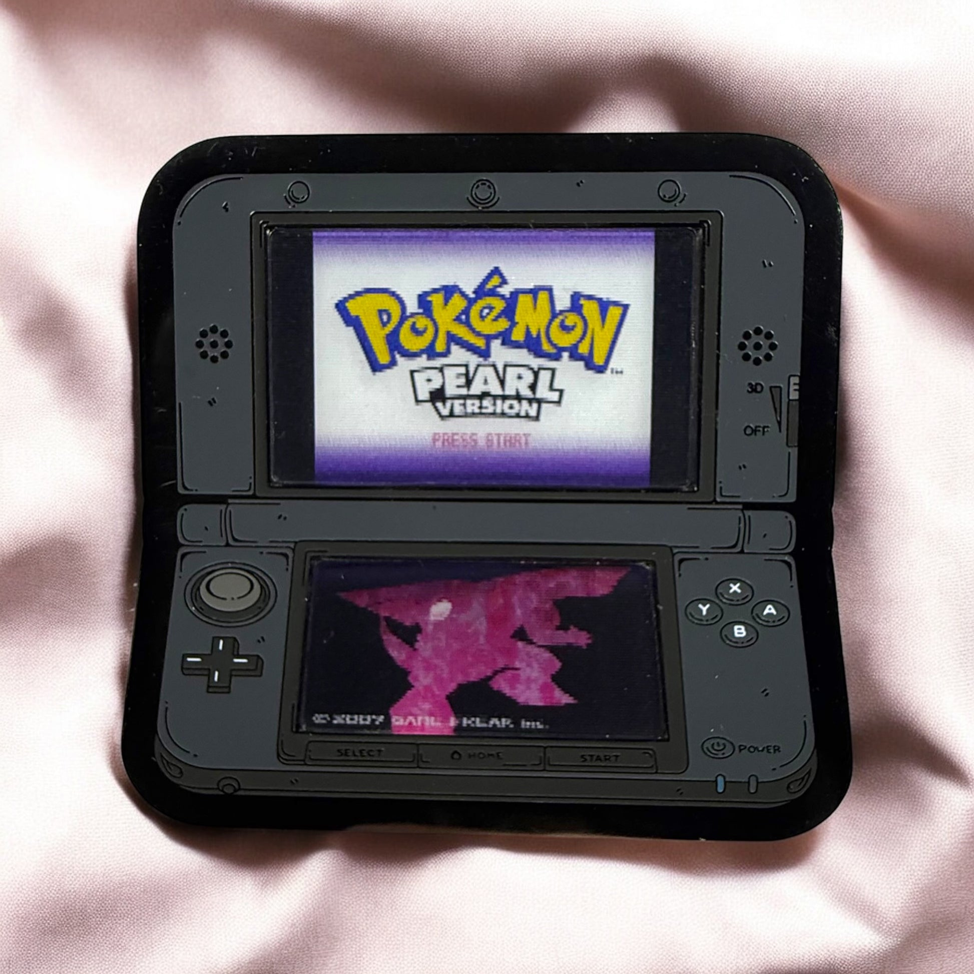 Nintendo DS with 'Pokémon Pearl Version' on screen on a pink fabric background