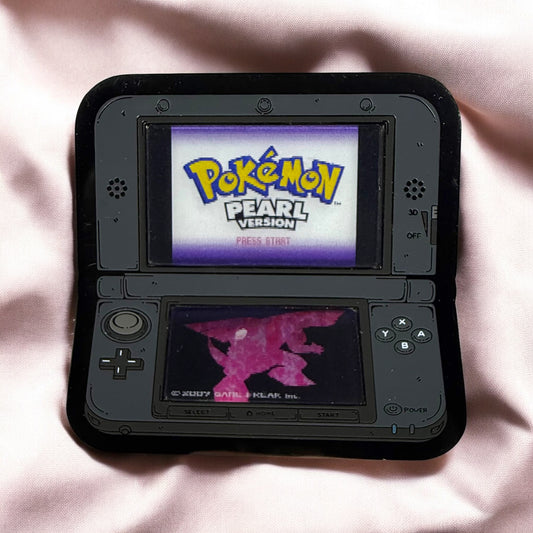 Nintendo DS with 'Pokémon Pearl Version' on screen on a pink fabric background