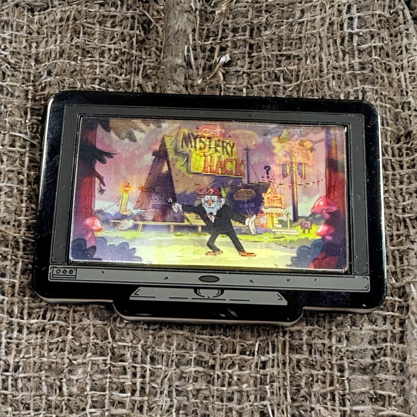 Small handheld gaming device with a colorful game screen on a textured fabric background