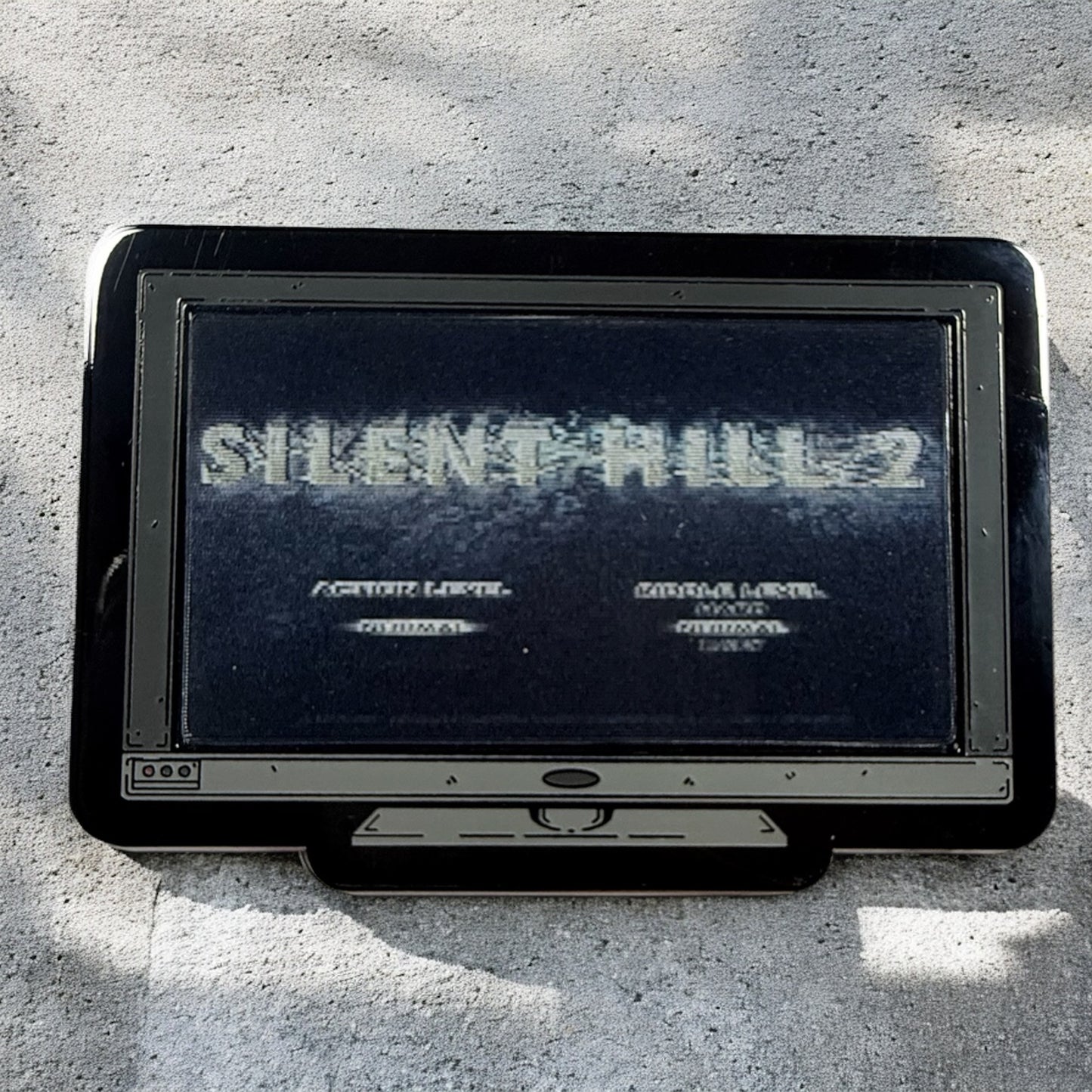 Vintage gaming console with 'Silent Hill 2' title screen on a concrete surface