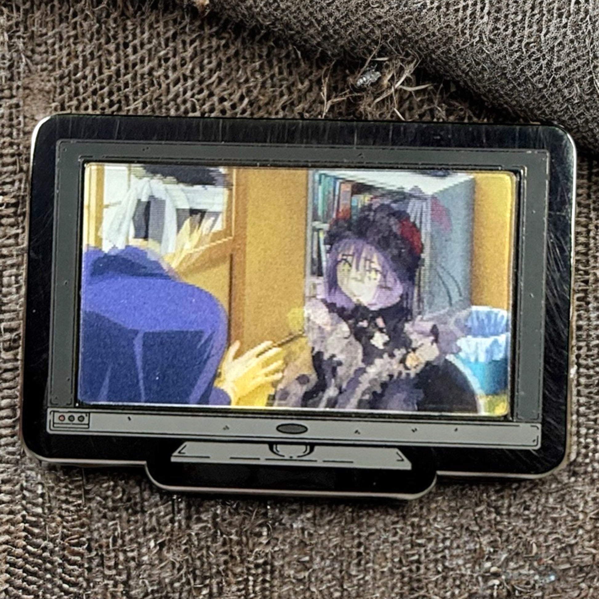 Small screen displaying a colorful scene with two people on a textured surface