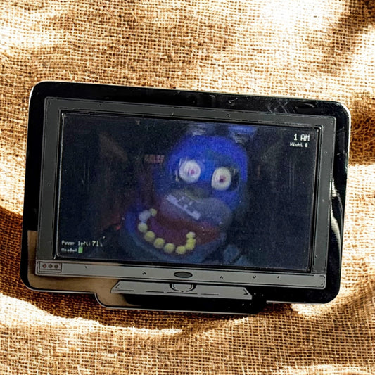 Small screen displaying a blue character with a red shirt on a textured brown background