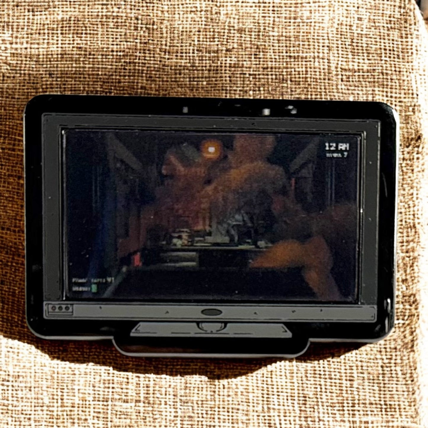 Small screen displaying a video on a textured fabric background