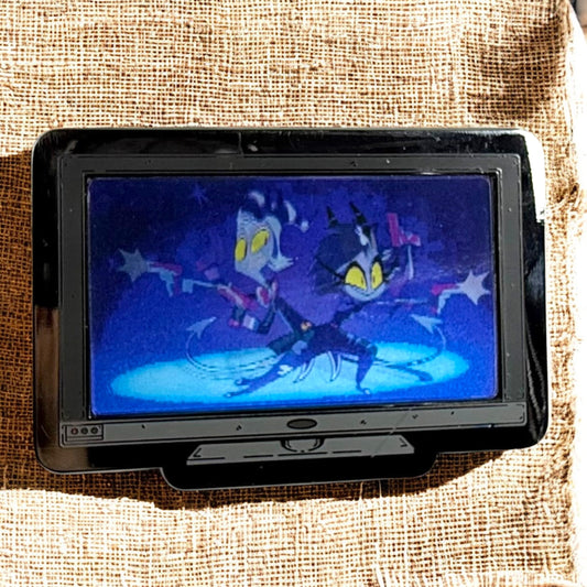 Small screen displaying an animated character on a textured fabric background