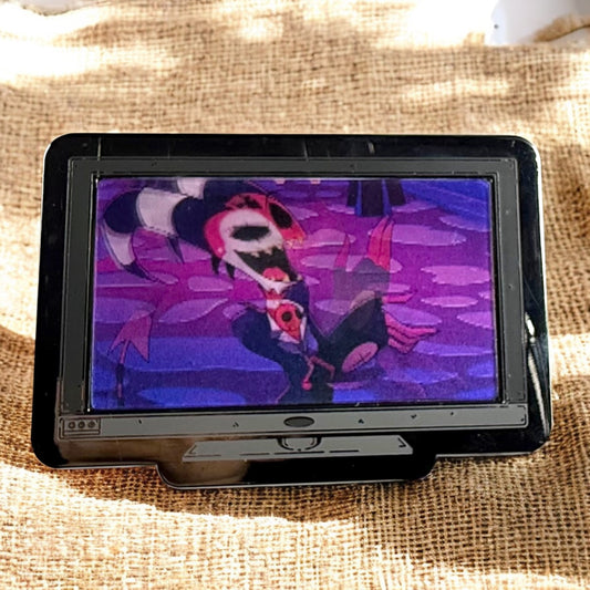 Small screen displaying a colorful character on a textured fabric background