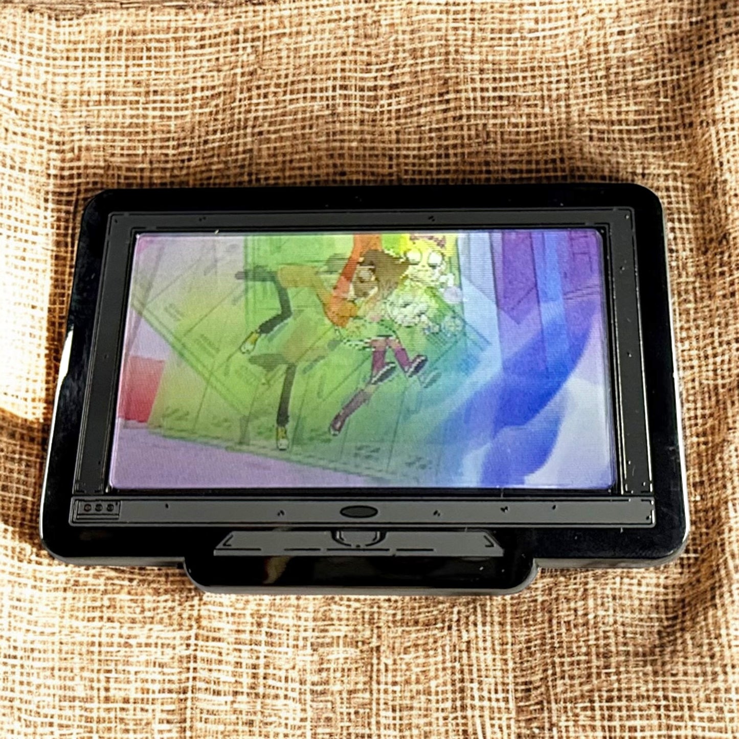 Small screen displaying colorful abstract art on a textured fabric background