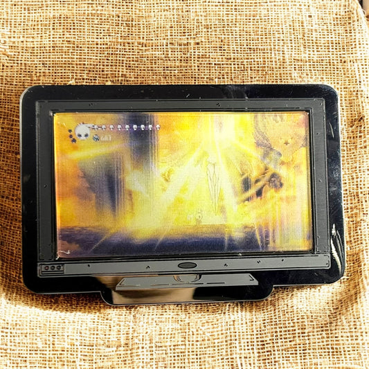 Small screen or monitor displaying a bright yellow and black abstract pattern on a textured beige background