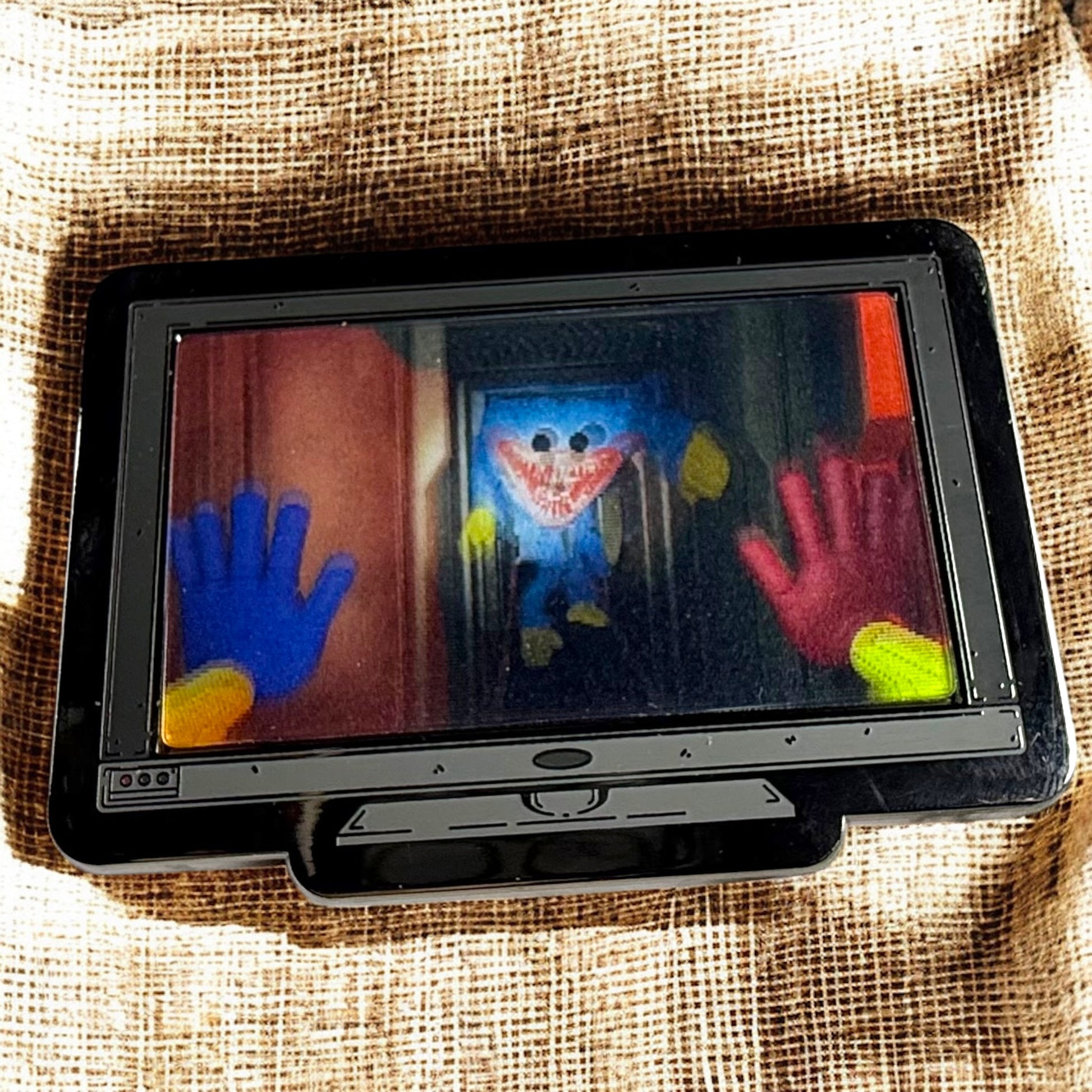 Tablet displaying a colorful handprint art project on a textured fabric background