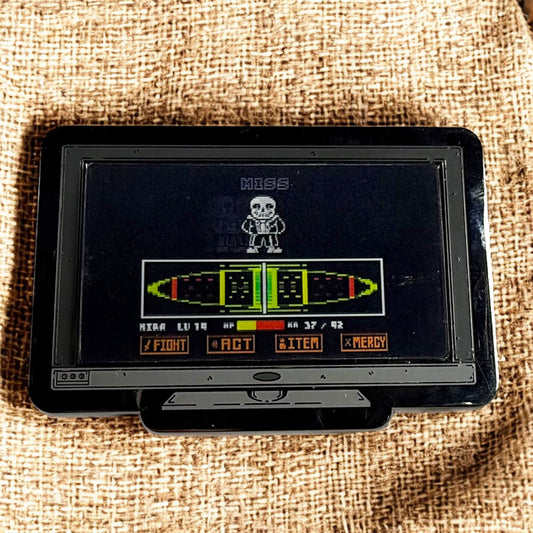 Vintage handheld gaming console with a screen displaying a game interface on a textured fabric background.