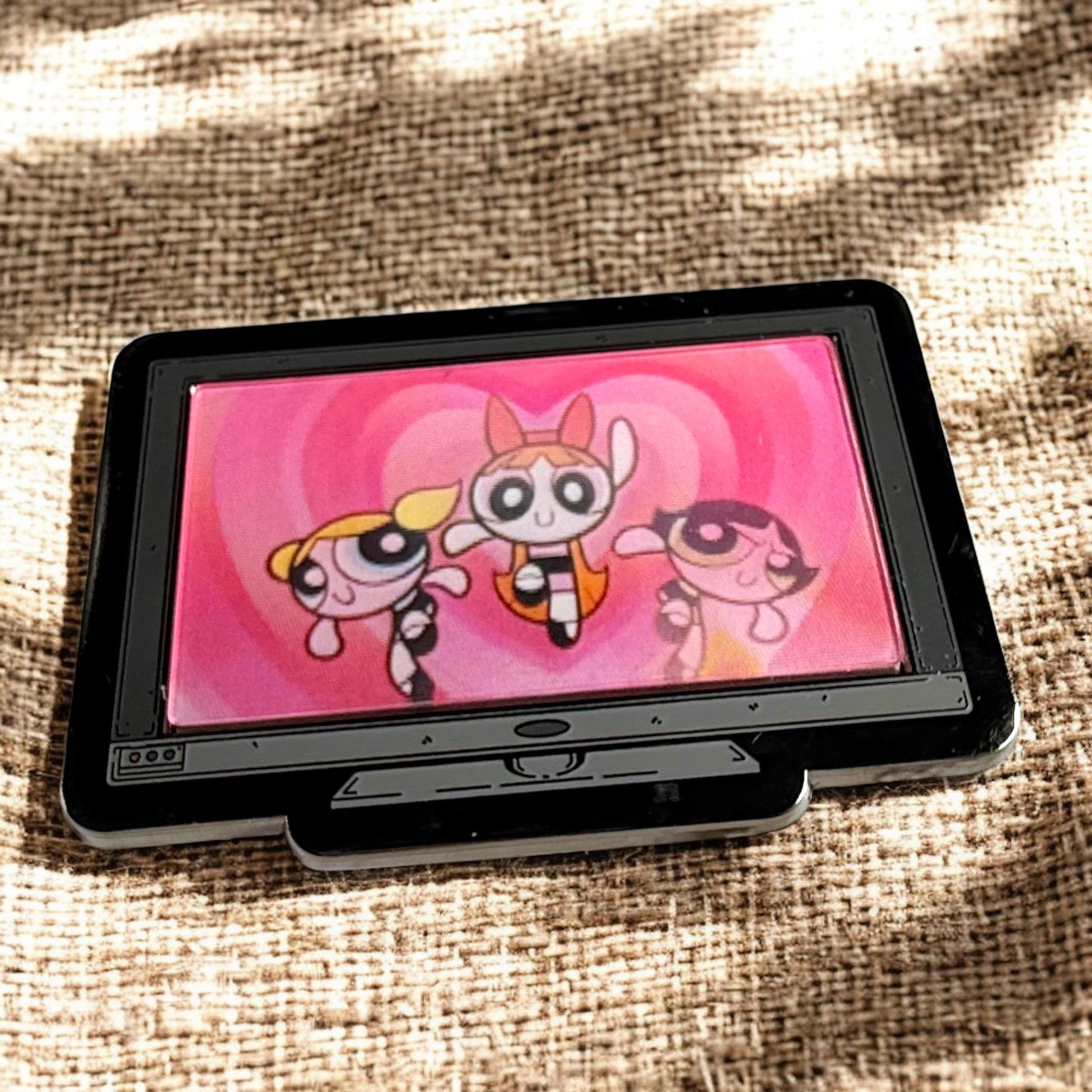 Small screen displaying cartoon characters on a textured fabric background