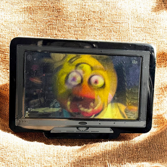 Small screen displaying a colorful character on a textured fabric background